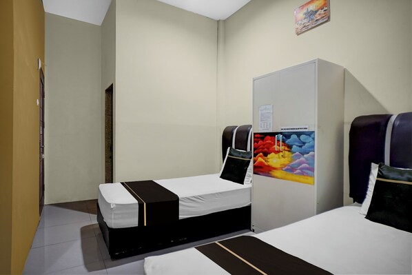 A hotel room with two beds, a wardrobe, and a painting on the wall. - OYO 94929 Penginapan Kalijaga Syariah (Medan)