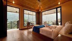 Camera da letto con un letto grande, una sedia e un tavolino. Ampie finestre offrono vista sull'esterno.