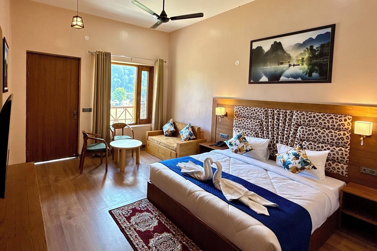 Une chambre d’hôtel avec un lit, un bureau, une chaise, une fenêtre et un tableau au mur.