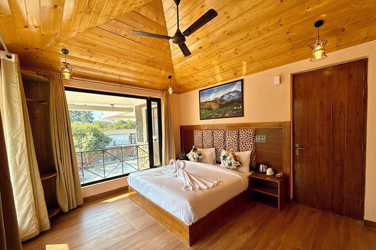 Une chambre avec un plafond en bois, un lit avec une literie blanche, une table de chevet et une fenêtre avec des rideaux.