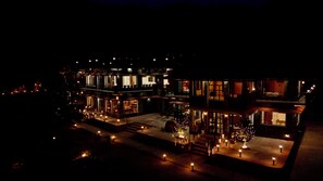 A multi-story building with illuminated windows and outdoor lighting, featuring a central courtyard with a Christmas tree and seating area. - TerraTrek Billora (Marchula)