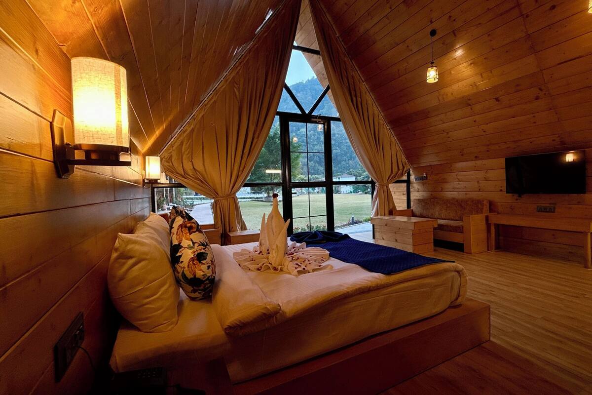 Une chambre dans une cabane en bois, avec un lit, une télévision et une grande fenêtre.