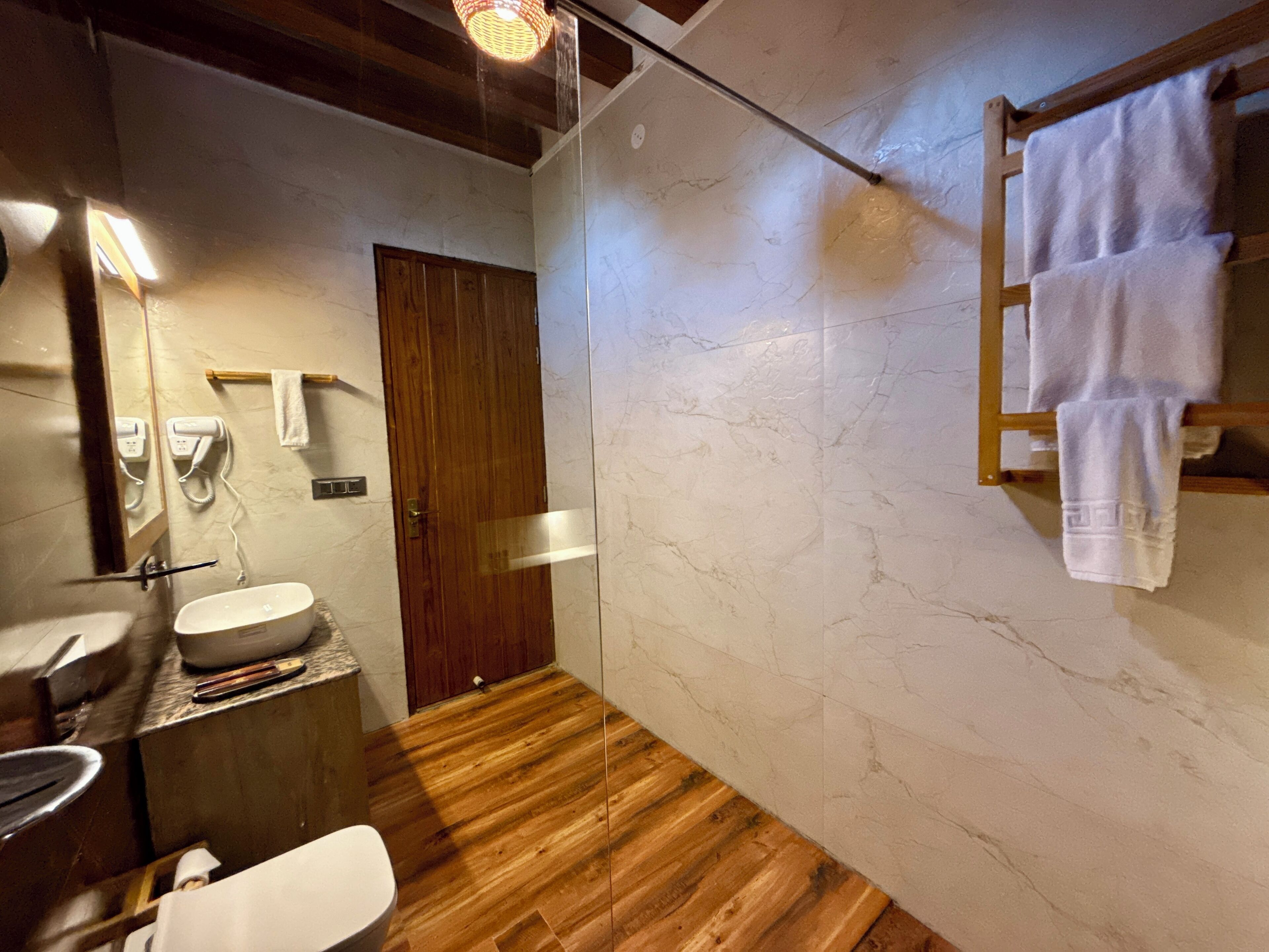 A bathroom with a wooden floor, a sink, a mirror, and a towel rack.