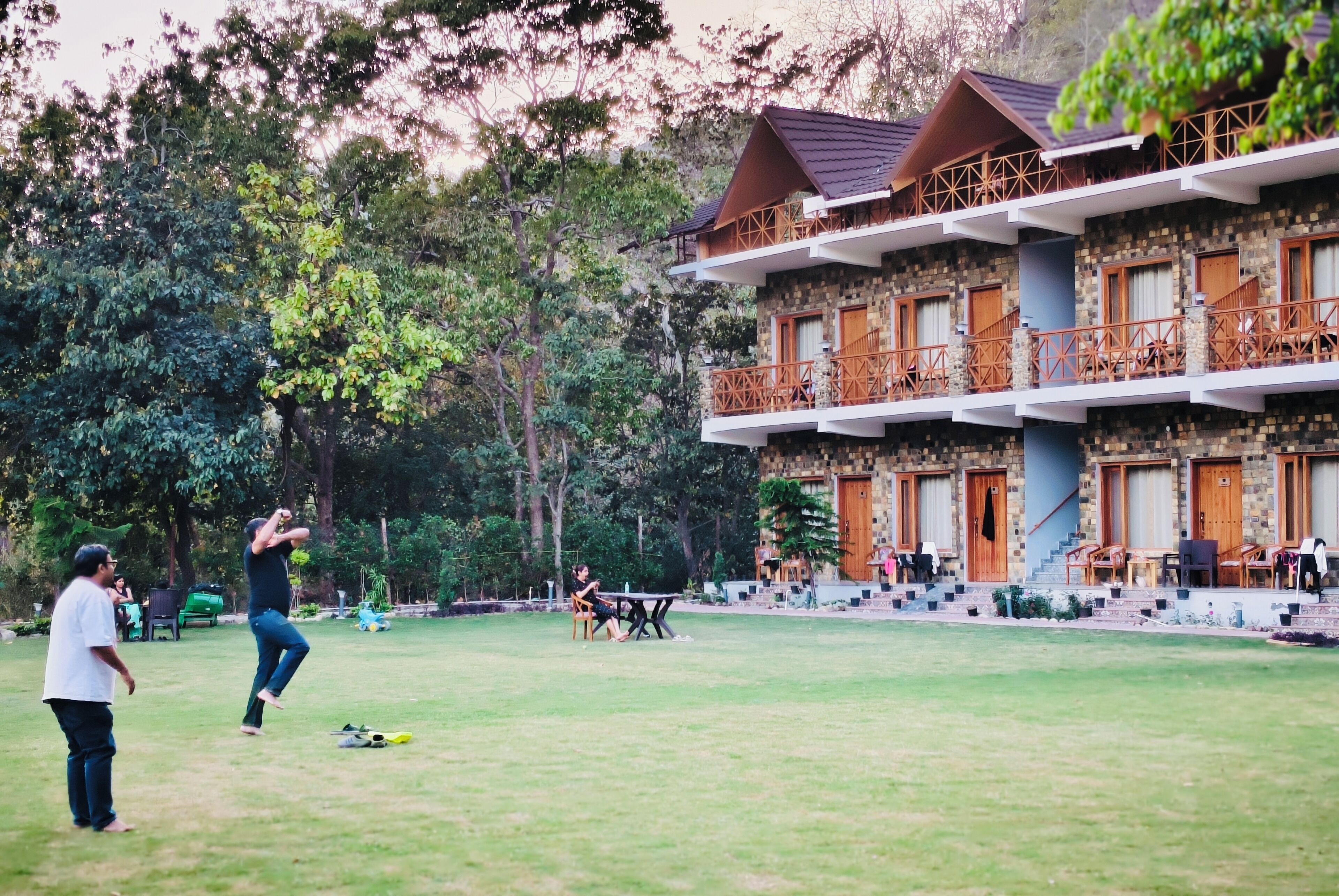 A multi-story building with balconies, a lawn, and outdoor seating.
