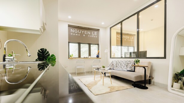 A modern living room with a sofa, chairs, a coffee table, and a large window. - Nguyen Homestay Phan Ton - District 1 (Ho Chi Minh City)