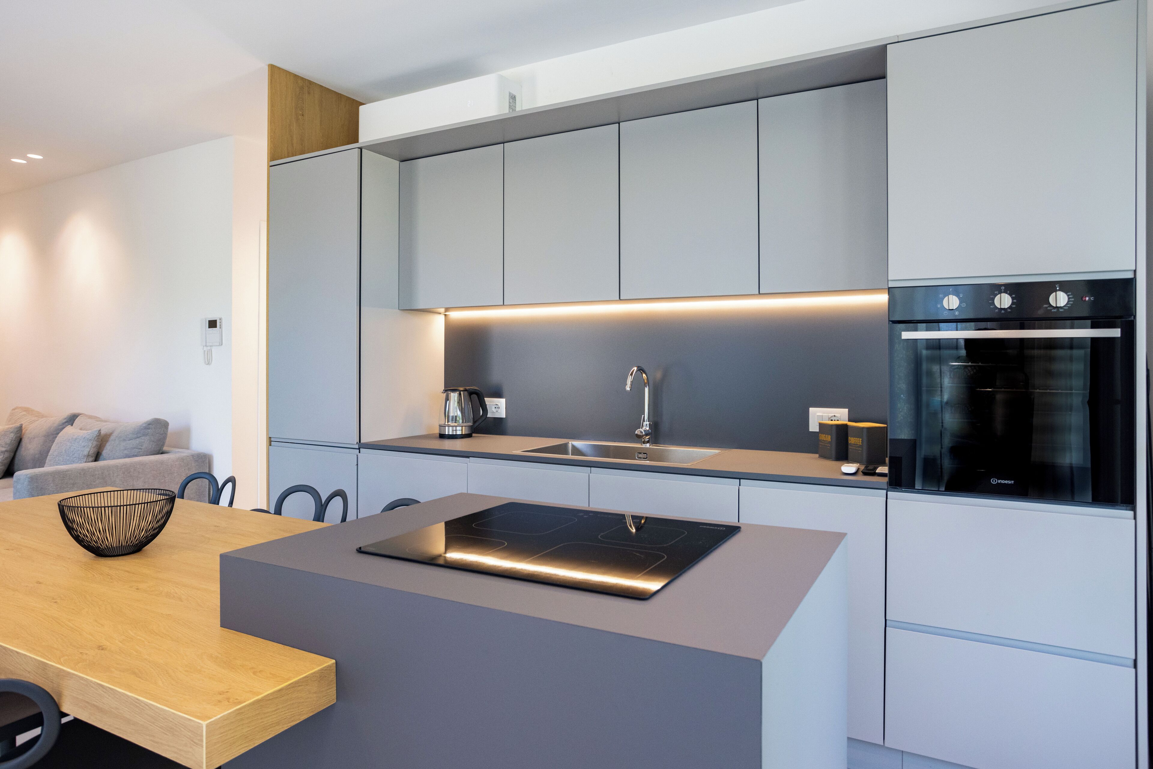 Ett modernt kök med en central köksö, inbyggda vitvaror och en minimalistisk design.
