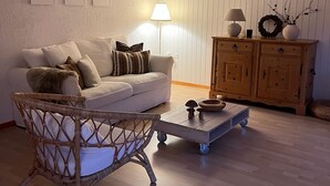 A cozy living room with a sofa, a wicker chair, a wooden coffee table, and a cabinet.