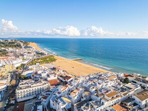 A coastal town with white buildings, a beach, and the sea. - Debonair Apartment (Albufeira)