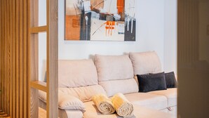 Ett modernt vardagsrum med en beige soffa, två hoprullade handdukar och en samtida, abstrakt målning på väggen.
