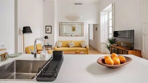 A modern kitchen with a sink, a dish rack, and a bowl of oranges on the counter. - 🌙 Lunero: Elegant One-Bedroom Retreat in Seville’s Historic Old Town (Sevilla)