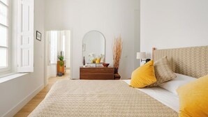 A bedroom with a bed, bedside table, mirror, and a dresser. - 🌙 Lunero: Elegant One-Bedroom Retreat in Seville’s Historic Old Town (Sevilla)