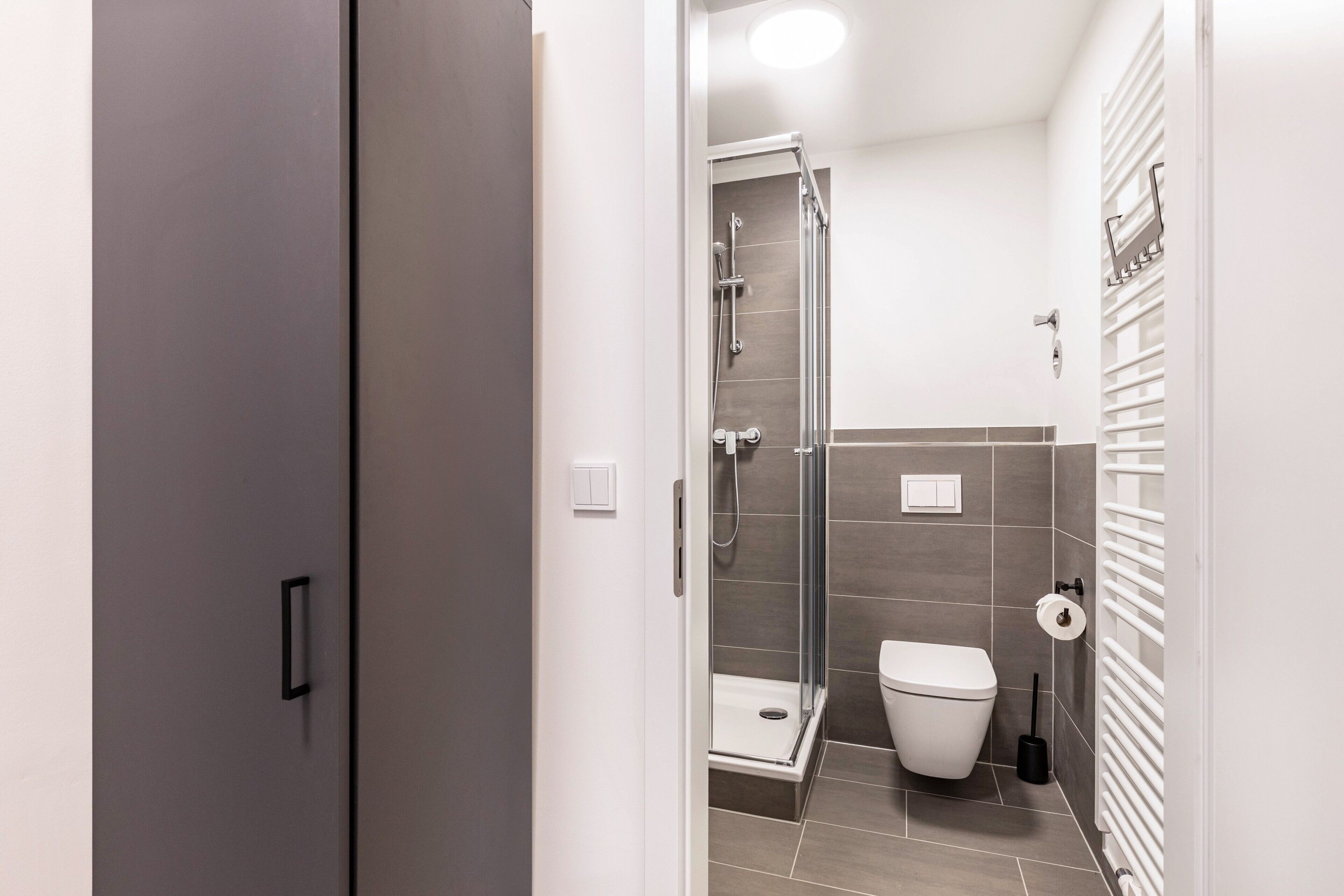 Une salle de bain moderne équipée d’une douche, de toilettes et d’un porte-serviettes.