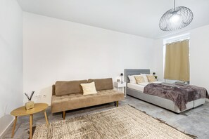 Une chambre à coucher comprenant un canapé, un lit, une table de chevet, une lampe et un luminaire décoratif.
