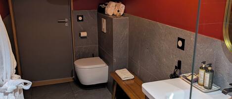 A modern bathroom with a white sink, a mirror, a bench, and a toilet.