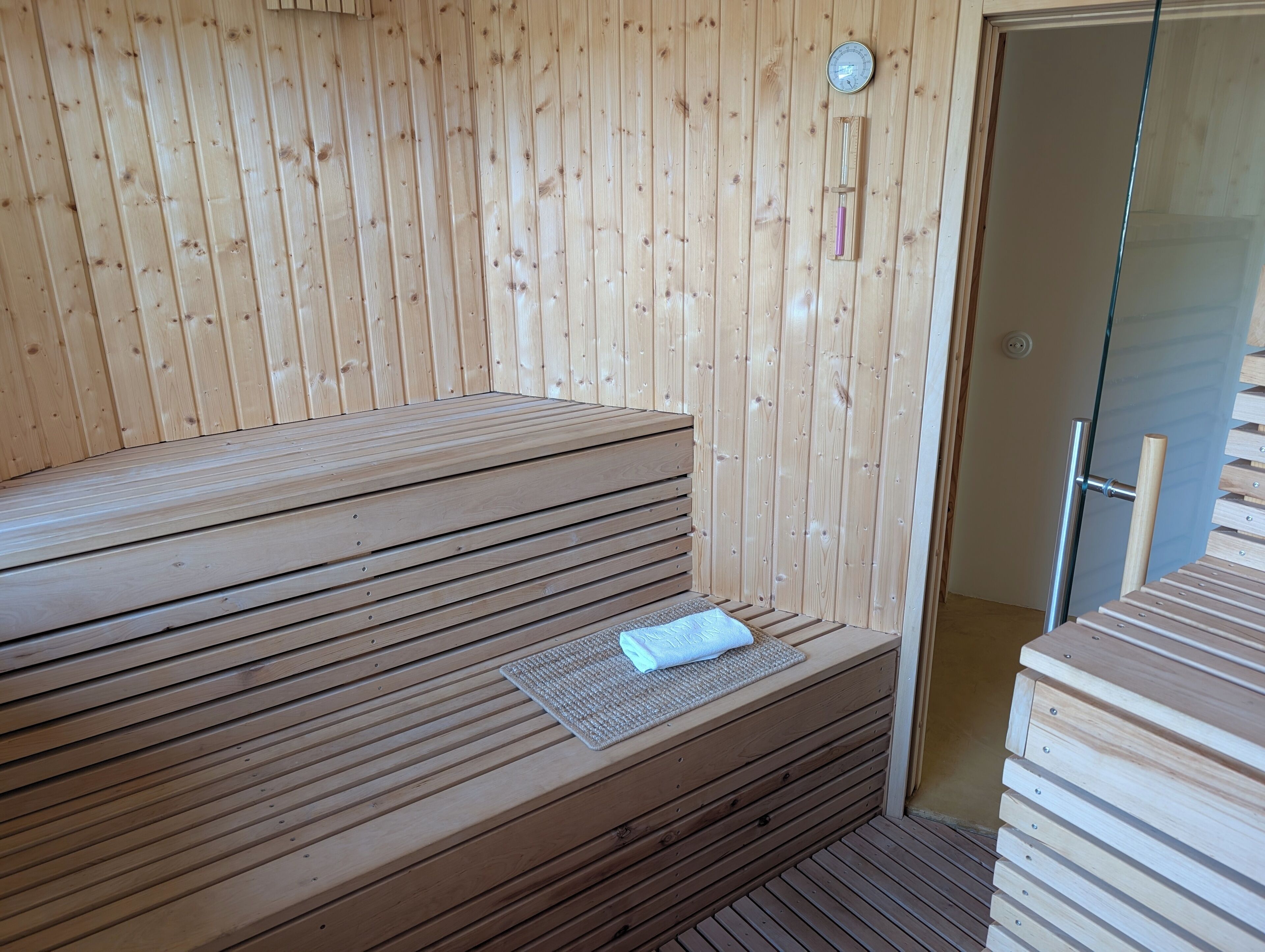 Uma sauna de madeira com bancos e porta de vidro.