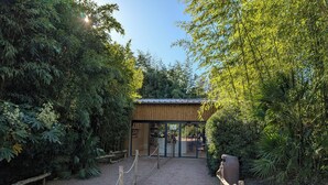A wooden building with a metal roof, surrounded by dense foliage. - Night Experience By Zoo Bordeaux Pessac (Pessac)