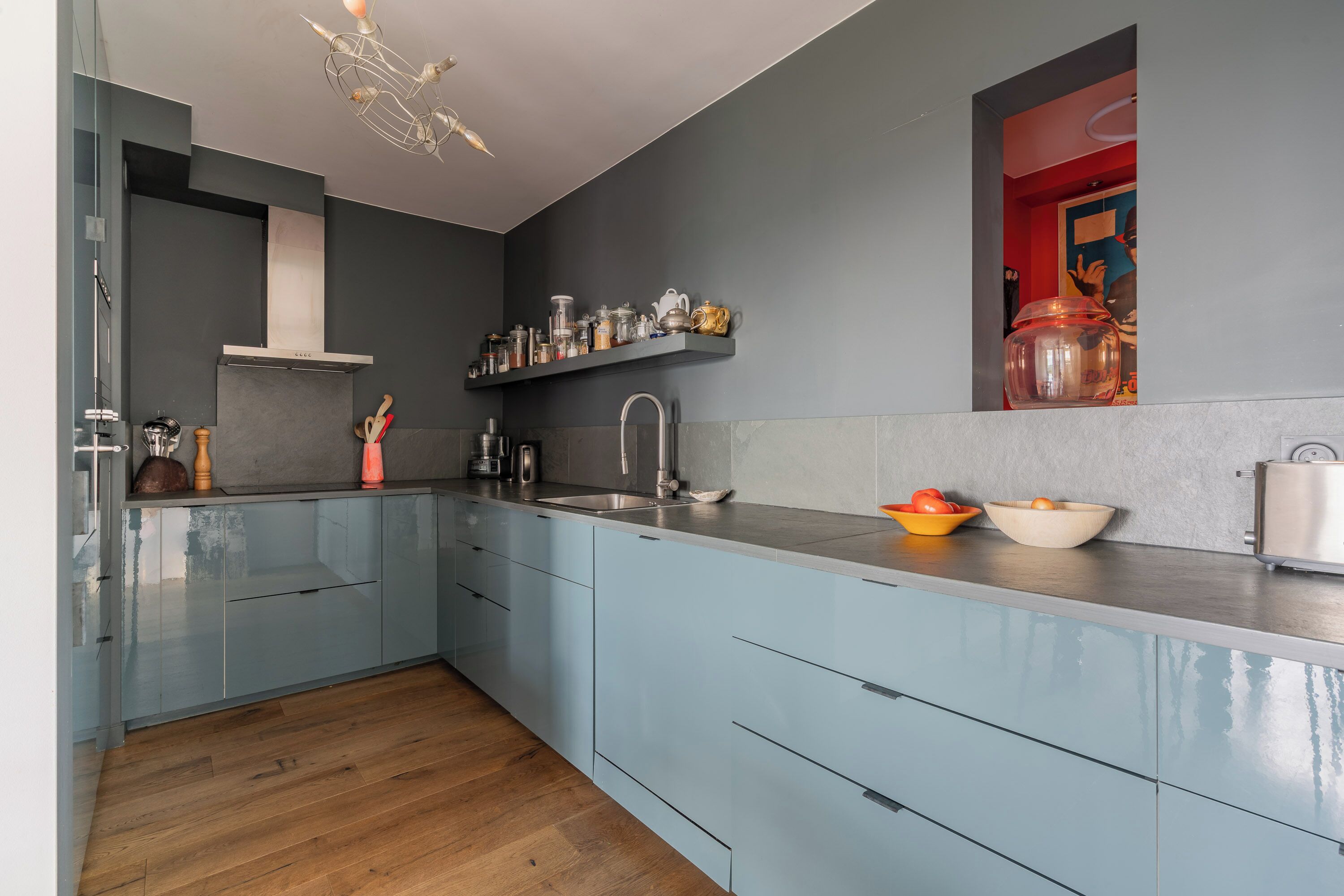A modern kitchen with light blue cabinets, a stainless steel sink, and a built-in range hood.