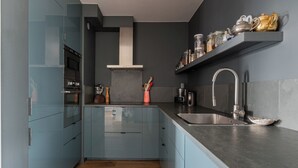 Una cucina moderna con mobili azzurri, un lavello in acciaio inossidabile e un forno integrato.