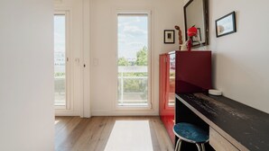 Una cucina moderna con pavimento in legno, un mobiletto rosso, un piano di lavoro bianco e un'ampia finestra vista verde.