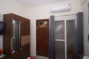 A room with a wardrobe, a door with a decorative panel, a sliding glass door with curtains, and an air conditioning unit. - Hotel Stay Bliss Marathahalli (Marathahalli, Bengaluru)