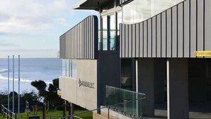 Ein modernes Gebäude mit einer gewölbten Fassade, großen Fenstern und Blick auf den Ozean.