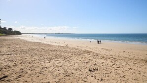 Une vaste plage de sable fin, avec un ciel dégagé et une mer calme.