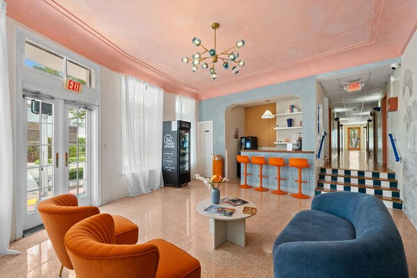 A lobby with orange and blue seating, a vending machine, and a staircase leading to another area.