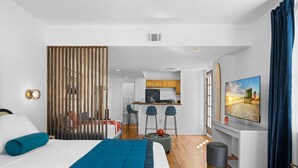 A modern hotel room with a bed, a desk, and a kitchenette. - Blue Flamingo Suites (Miami Beach)