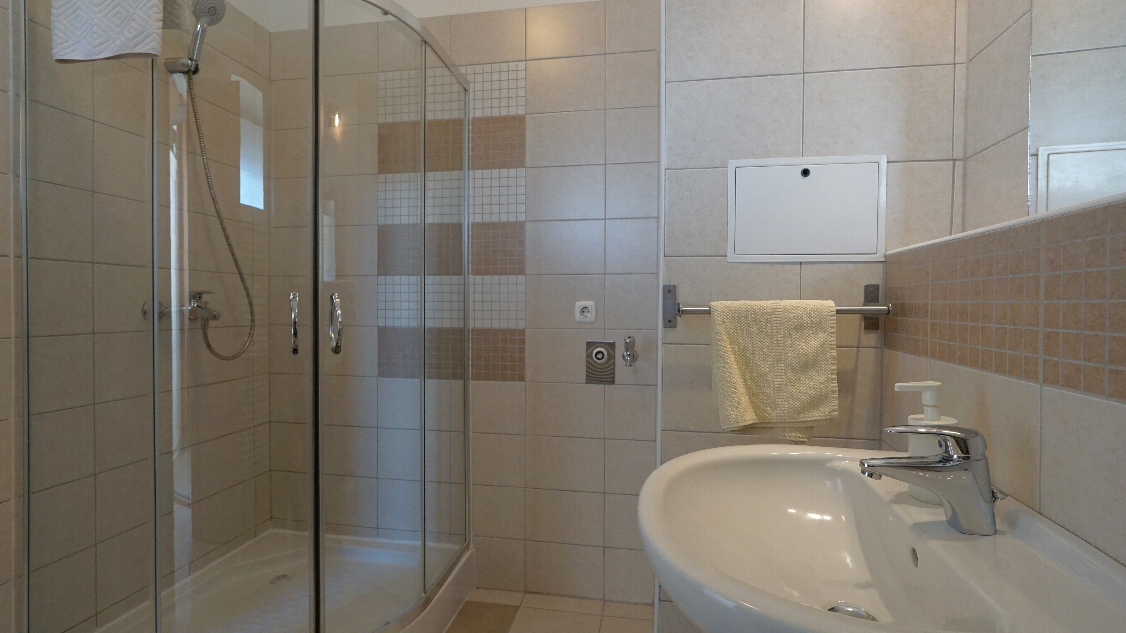 Une salle de bain moderne avec une douche à parois de verre, un lavabo blanc et un porte-serviettes.