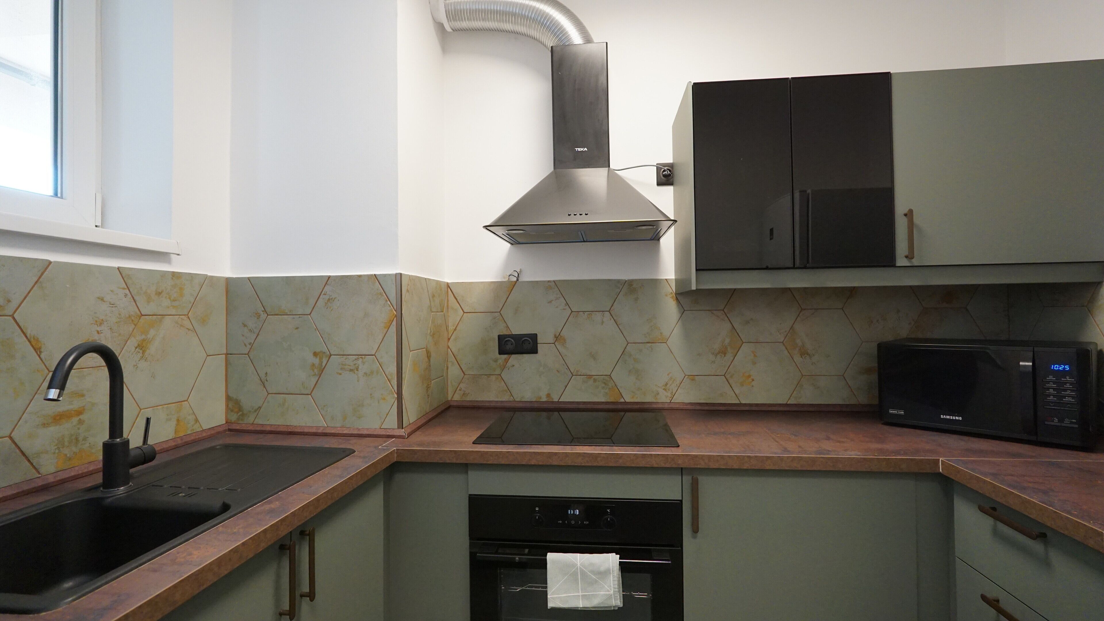 A kitchen with a stainless steel range hood, a microwave, and a dishwasher.