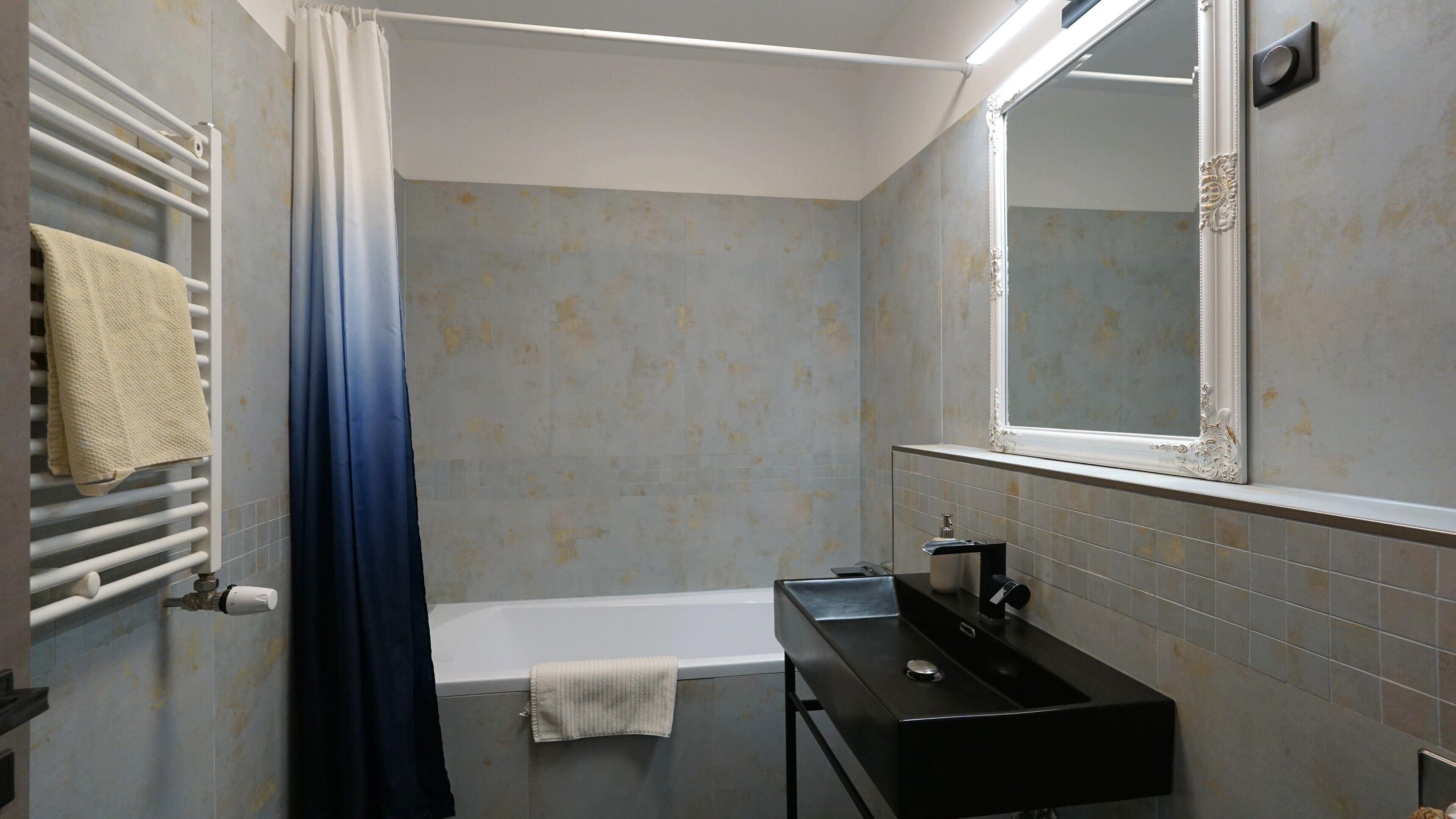 A bathroom with a bathtub, a sink, a towel rack, and a mirror.