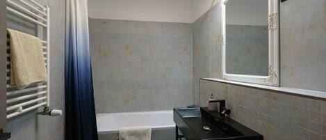 A bathroom with a bathtub, a sink, a towel rack, and a mirror.