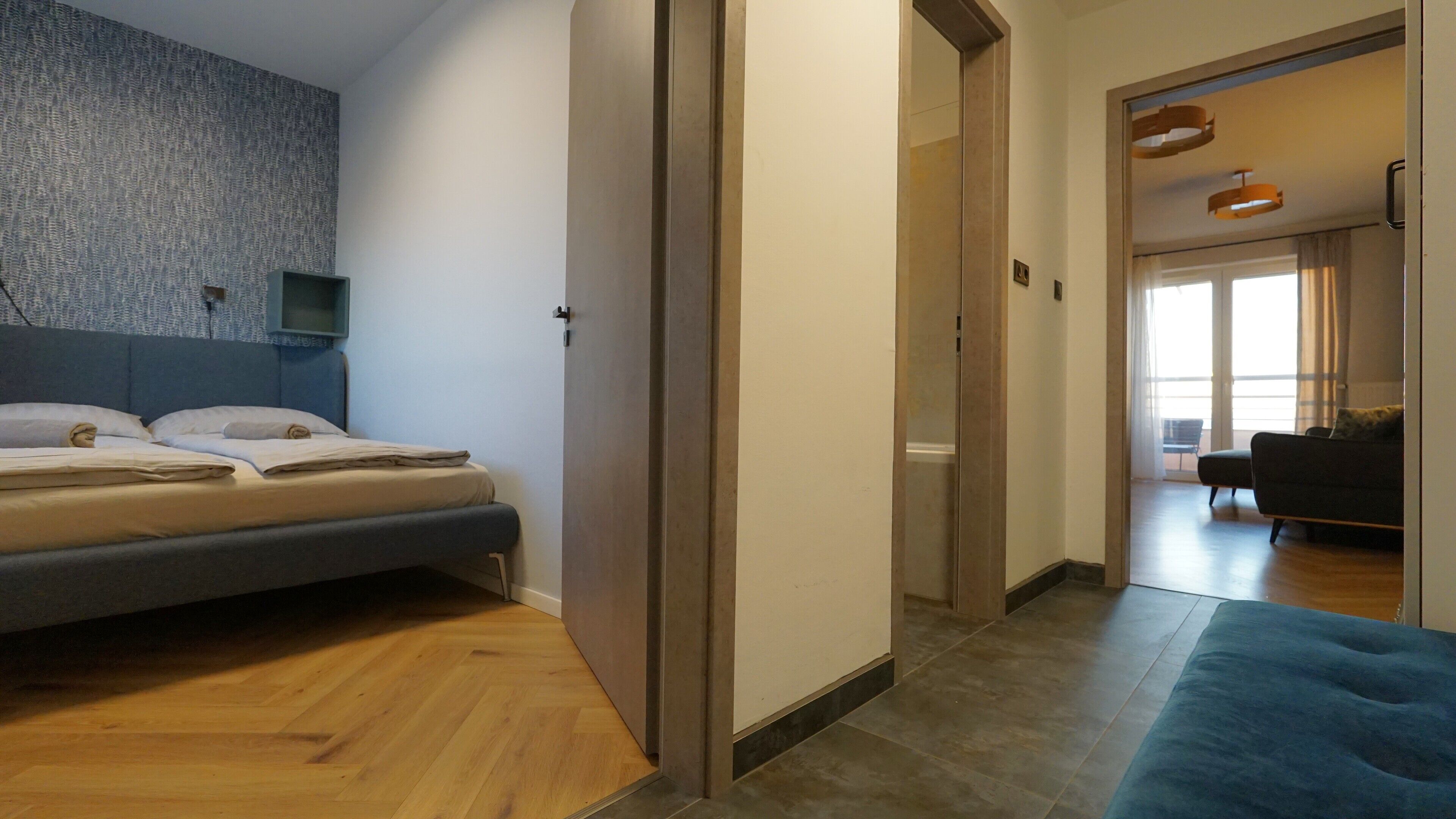 Ein modernes Schlafzimmer mit einem Bett, einem an der Wand montierten Fernseher und Holzboden.