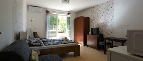 A bedroom with a bed, a desk, a TV, and a wardrobe.
