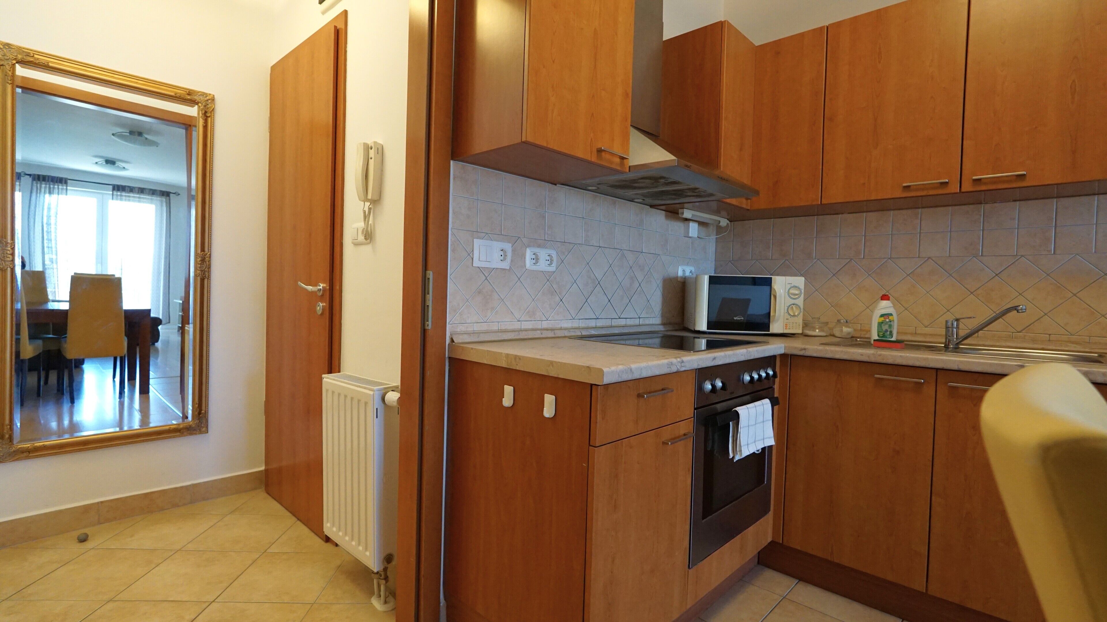 Una cocina compacta con armarios de madera, un microondas integrado, una estufa y un radiador.