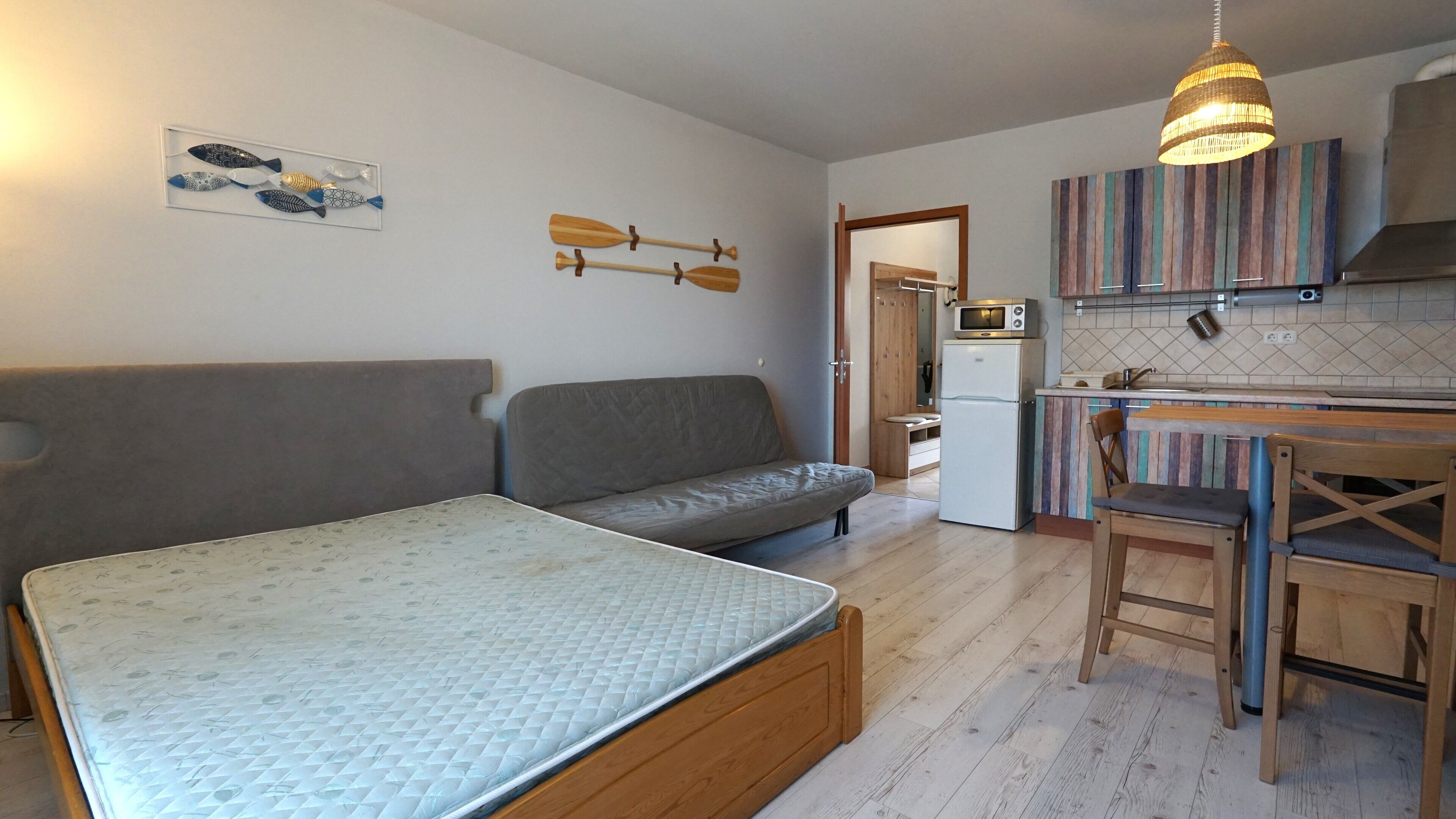 A compact living space with a sofa, a bed, a kitchenette, and a dining area.
