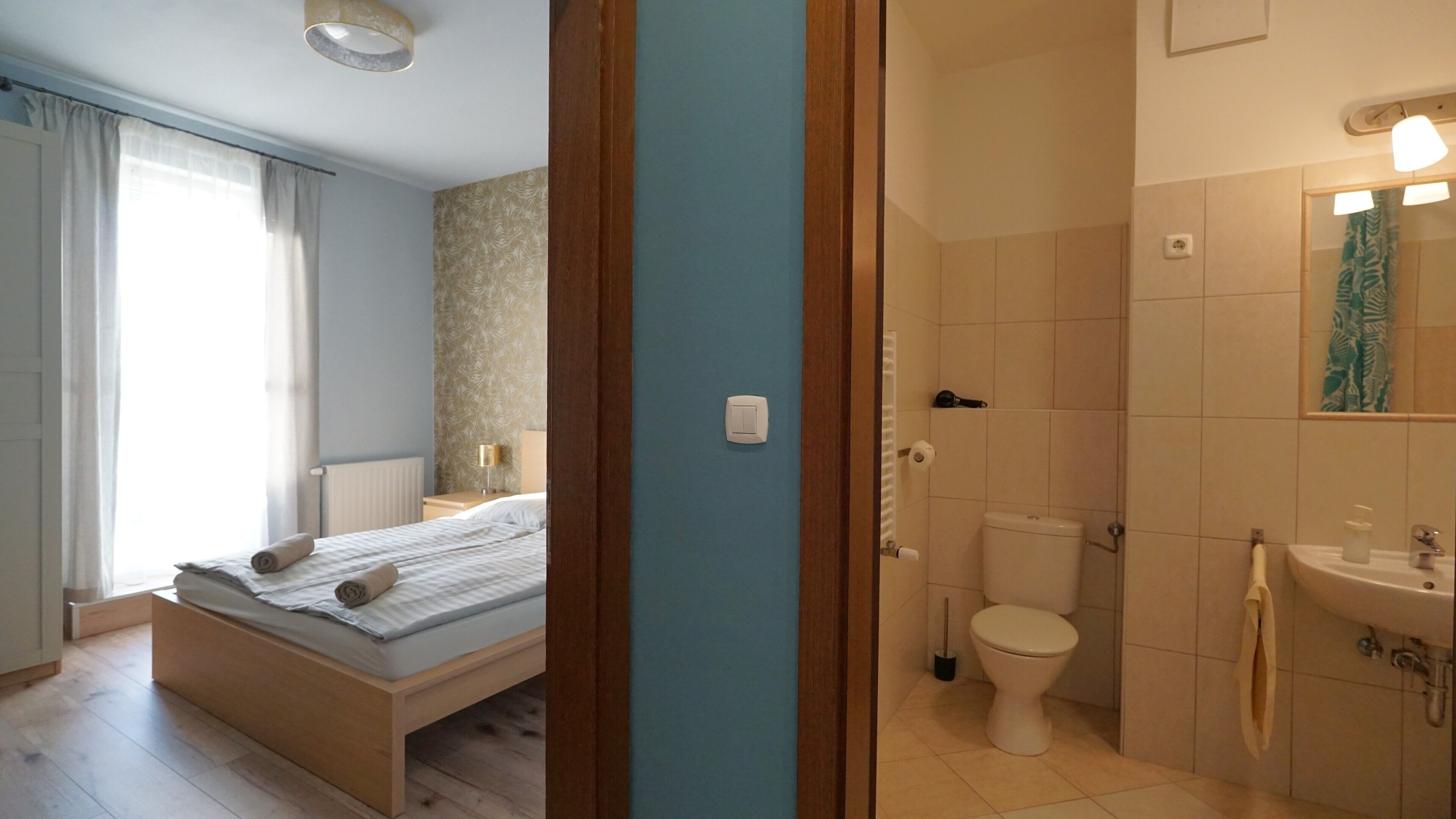 Ein Schlafzimmer mit Bett, ein Badezimmer mit Toilette und Waschbecken sowie ein Duschbereich.