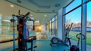 A gym with exercise equipment, large windows, and a view of the outdoors. - Club218 Wellness Apartments (Siófok)