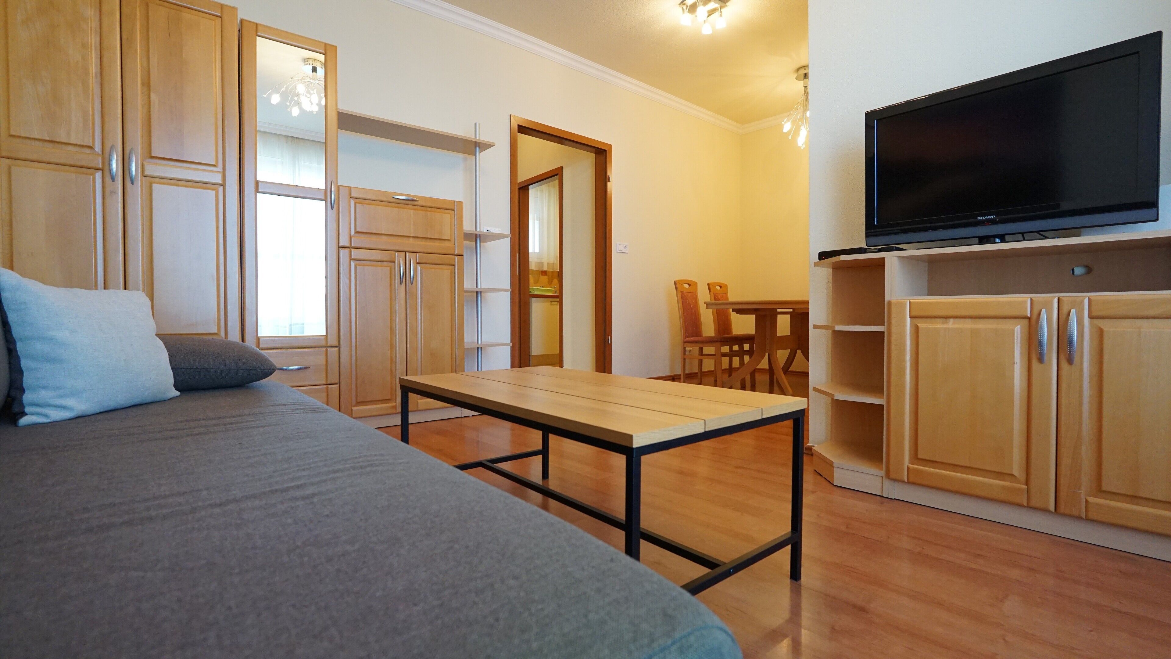 A bedroom with a bed, a wooden table, a TV, and a wardrobe.