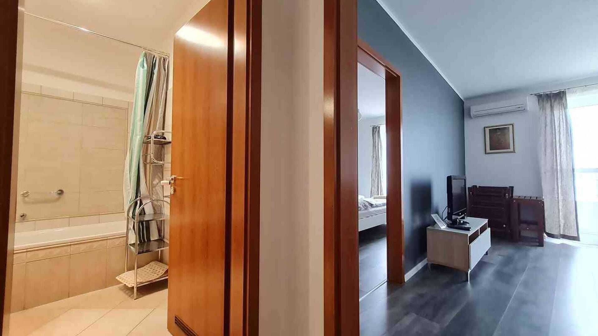 A hotel room with a shower, a bed, a TV, and a desk.