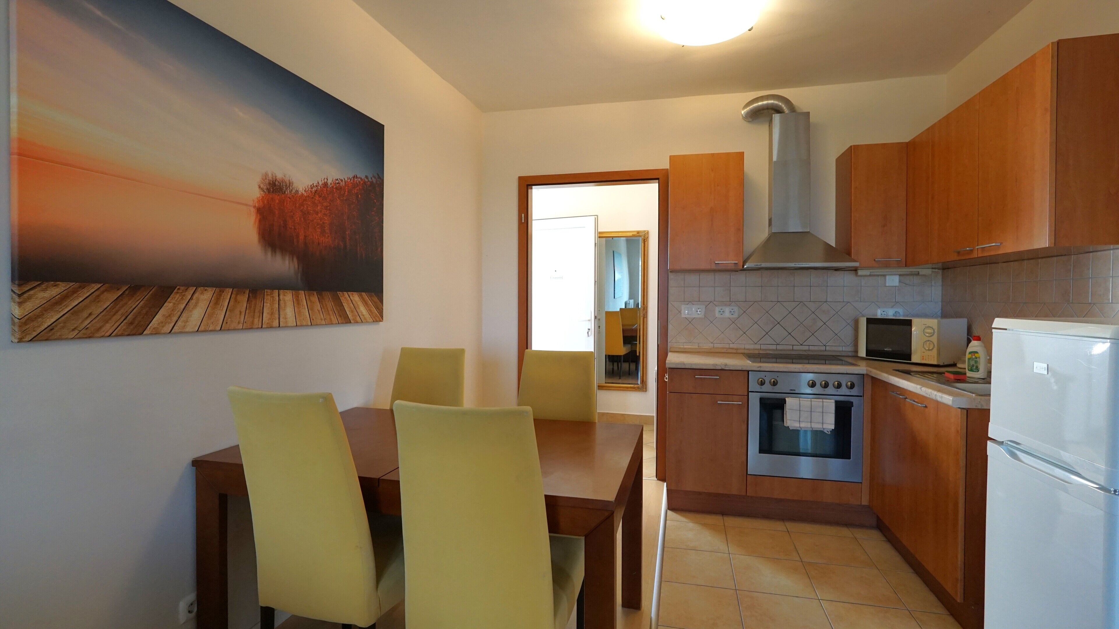 Una cocina moderna con armarios de madera, una campana extractora de acero inoxidable, un microondas y un refrigerador.