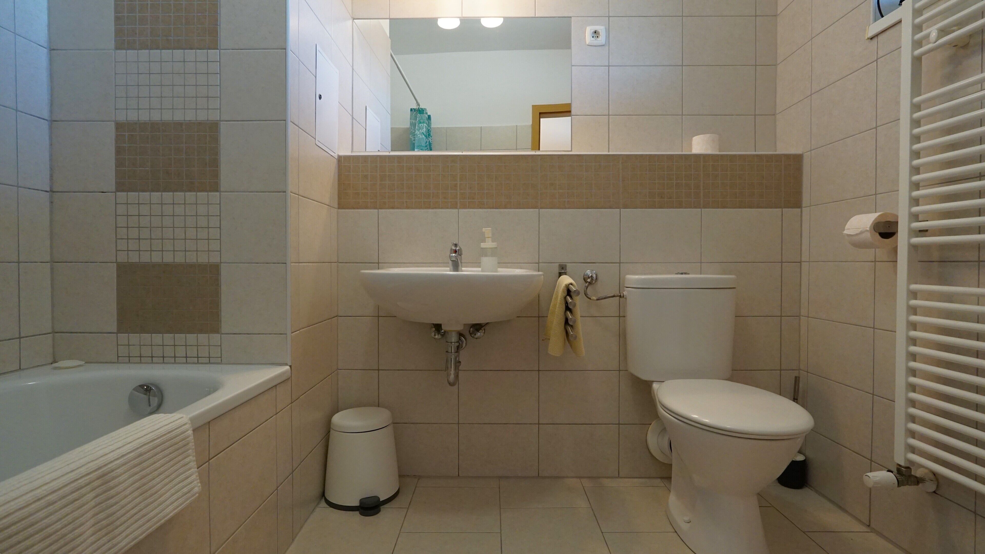 Un bagno con vasca, lavandino, water e porta asciugamani.
