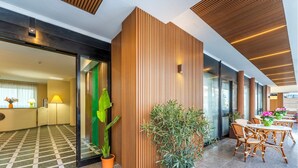 A modern hotel lobby with a checkered floor, wooden panel walls, and a seating area with wicker chairs and tables. - Rina Sea Apartments (Alghero)