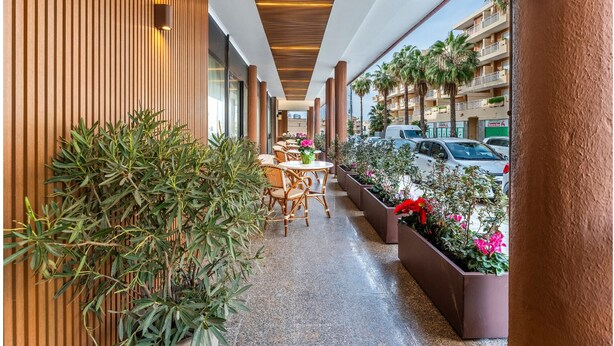 A corridor with wooden paneling, outdoor seating, and potted plants. - Rina Sea Apartments (Alghero)