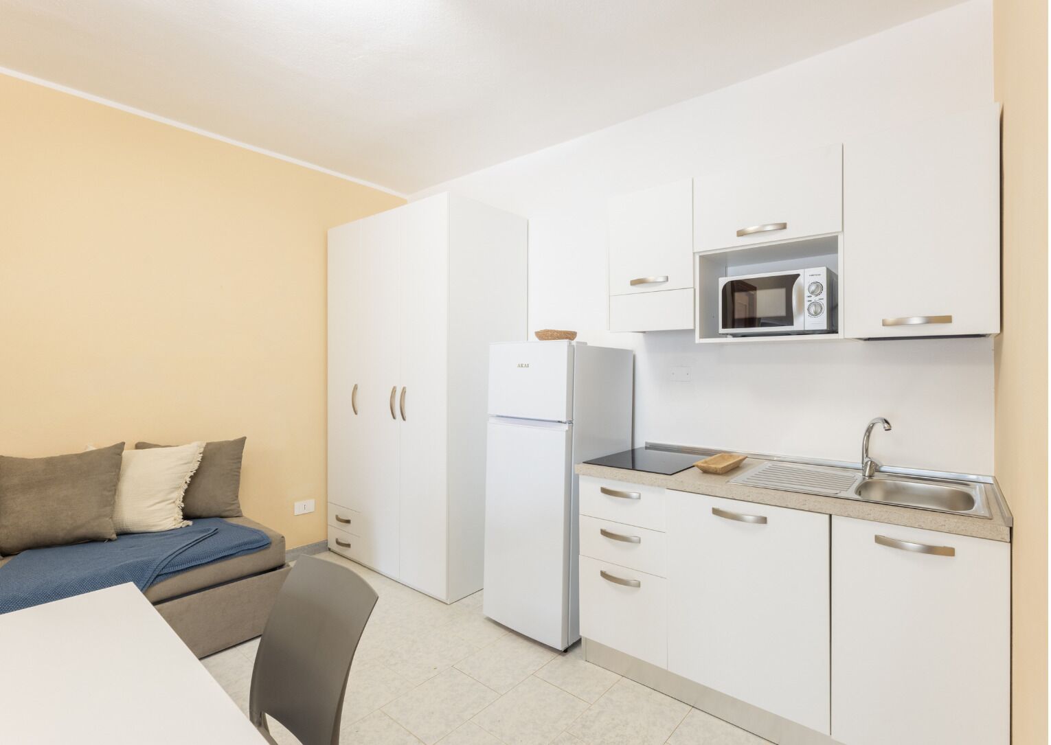 Una kitchenette compacta equipada con refrigerador, microondas y pileta. Hay un pequeño comedor con una mesa y una silla.