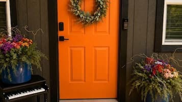 A wooden door with a wreath, a piano, and potted plants.