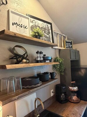 A kitchen with wooden shelves, a coffee maker, and a sign with text.