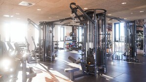 Un gimnasio con diversas máquinas de ejercicio, una banca y un espejo grande.