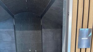 Una sala de sauna con puerta de madera, marco de puerta metálico y un letrero que dice 'DAMPBAD'.