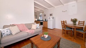 En stue med sofa, sofabord og spiseområde med stole og bord.